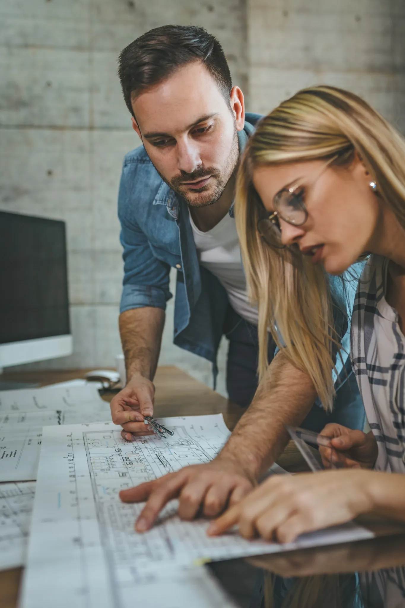 Dos profesionales trabajando sobre planos técnicos en un entorno de diseño, ejemplo práctico para estudiantes de cursos de AutoCAD.